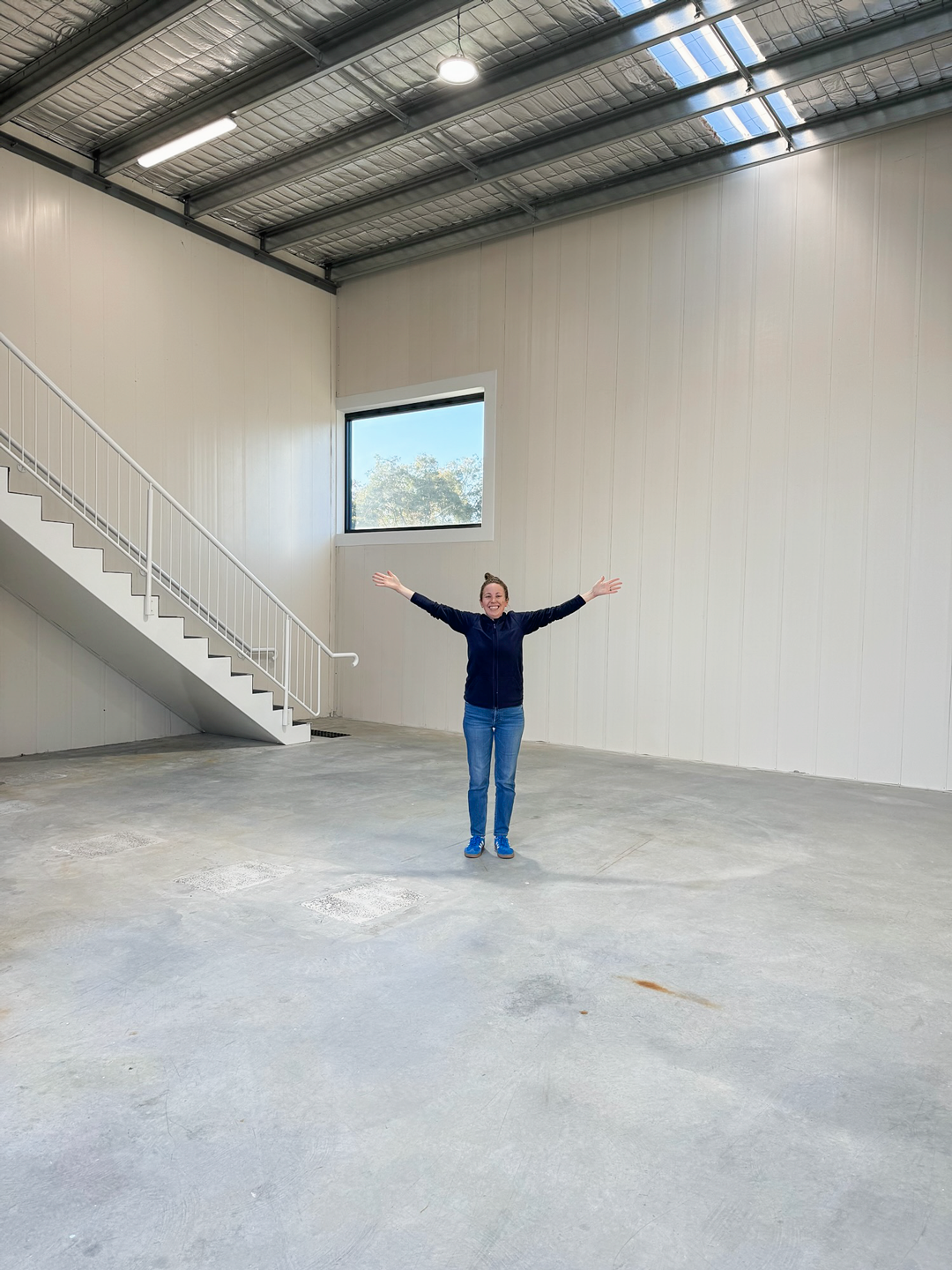 Irene with arms outstretched in the empty new Clean Nectarine warehouse, starting over
