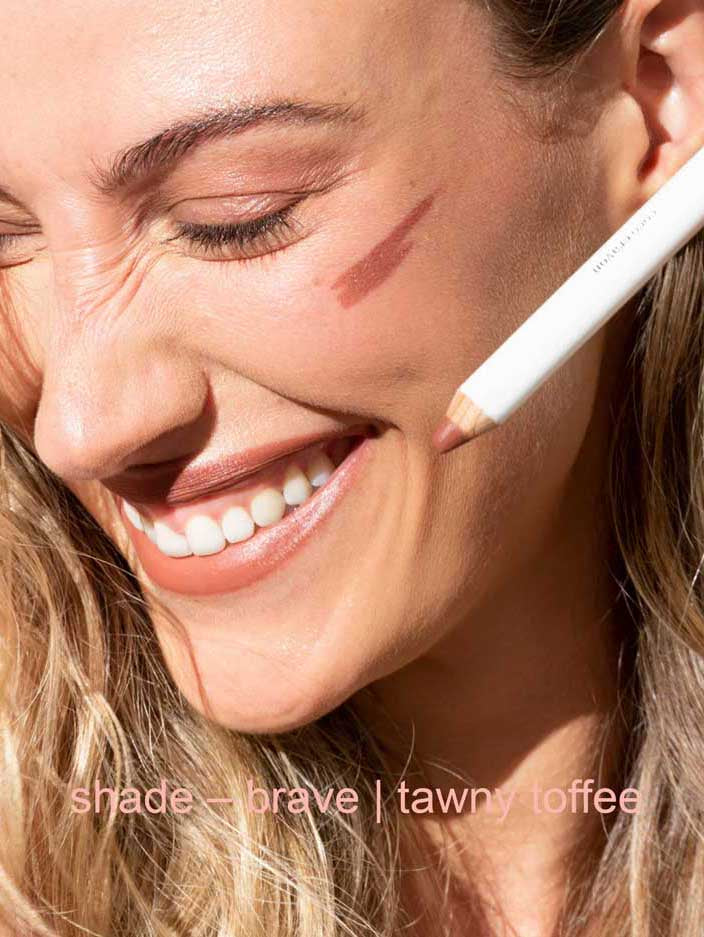 Woman applying makeup with a pencil, close-up of face.