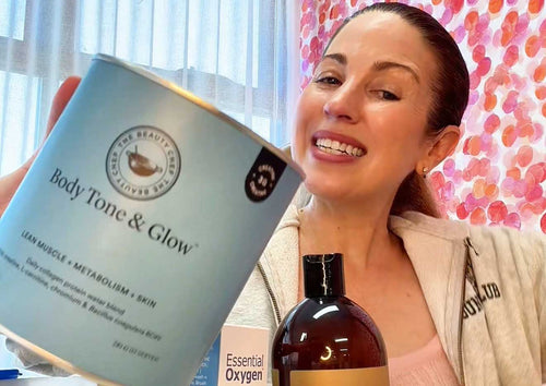 Irene Falcone, founder of Clean Nectarine, in her office in front of bright pink and peach wallpaper, holding a tub of The Beauty Chef Body Tone & Glow in blue packaging
