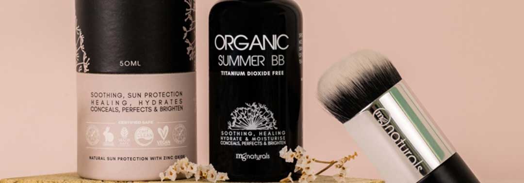 A black bottle of Organic Summer BB cream, a cylindrical product container, and a VF Naturals makeup brush are displayed against a beige background.