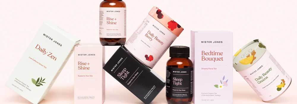A lineup of Mister Jones wellness products, including supplement bottles and boxes with names like Daily Zen, Rise + Shine, Sleep Tight, Bedtime Bouquet, and Daily Beauty Greens.