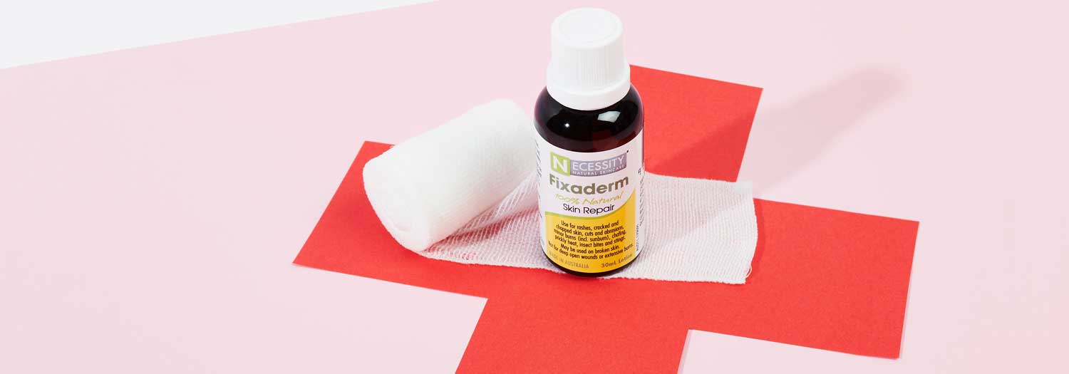 A bottle of Fixaderm skin repair solution and a rolled bandage rest on a piece of white gauze, placed over a red cross on a pink background.