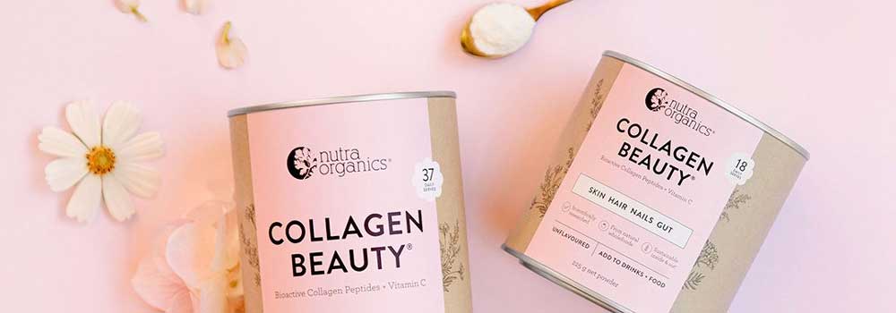 Two Nutra Organics Collagen Beauty containers on a pastel pink background, with flowers, a spoon of powder, and petals around them. The containers highlight benefits for skin, hair, nails, and gut.