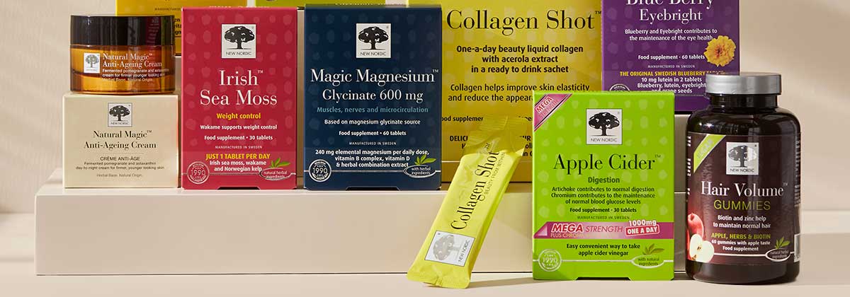 A display of New Nordic wellness products, including supplements like Irish Sea Moss, Apple Cider, Collagen Shot, Blue Berry, and a jar of Hair Volume Gummies on a beige background.