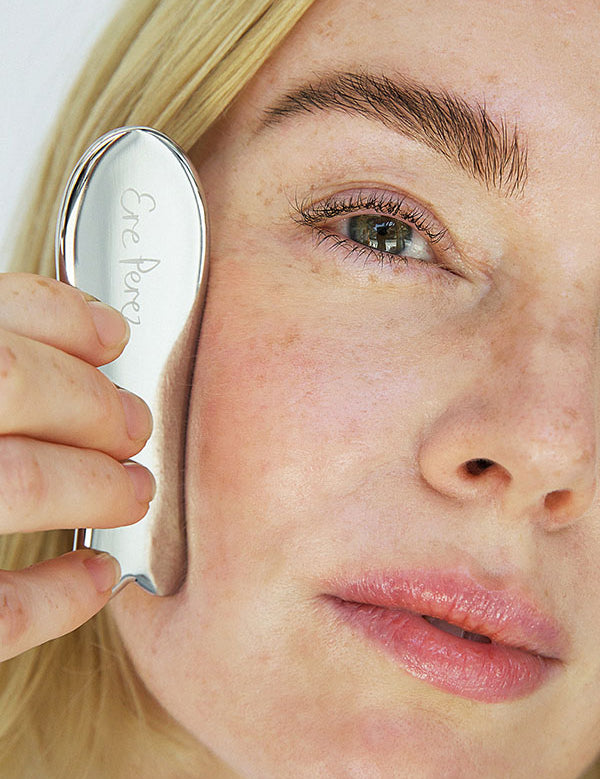 Woman gliding the Ere Perez Steel Face Tool along her cheekbone