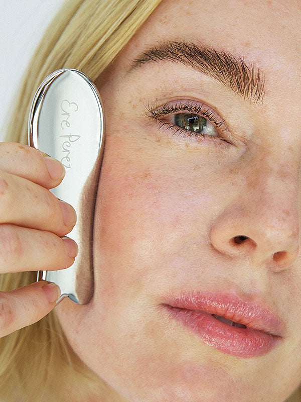 Woman gliding the Ere Perez Steel Face Tool along her cheekbone