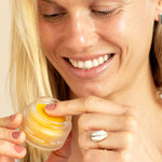 Smiling woman dipping a finger into the Ere Perez Papaya SOS Marmalade jar