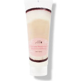 A white 100% Pure Coconut Shower Gel tube stands on a translucent flip-top cap. A pale pink oval label appears over a photograph of white coconut flesh and dark brown shell.