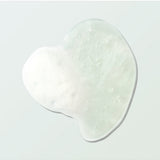 A clear Coconut Shower Gel swatch forms an irregular rounded pool on a pale mint surface. Tiny bubbles and a patch of white foam are visible within the gel.