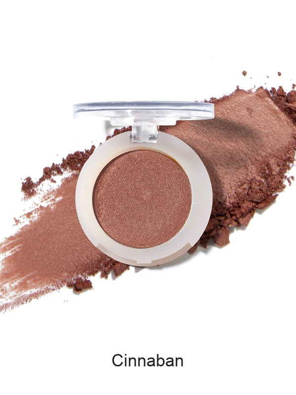 100% Pure Fruit Pigmented Eye Shadow in Cinnaban, showing an open compact beside a sweep of matching loose powder on white, with the shade name Cinnaban printed below.