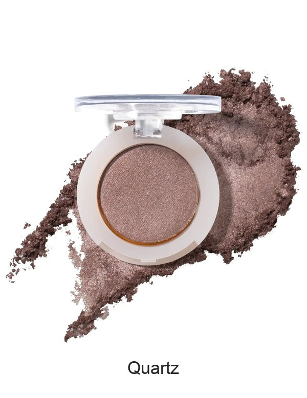 100% Pure Fruit Pigmented Eye Shadow in Quartz, showing an open compact beside a sweep of matching loose powder on white, with the shade name Quartz printed below.