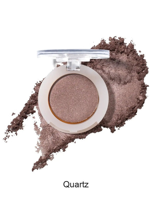 100% Pure Fruit Pigmented Eye Shadow in Quartz, showing an open compact beside a sweep of matching loose powder on white, with the shade name Quartz printed below.