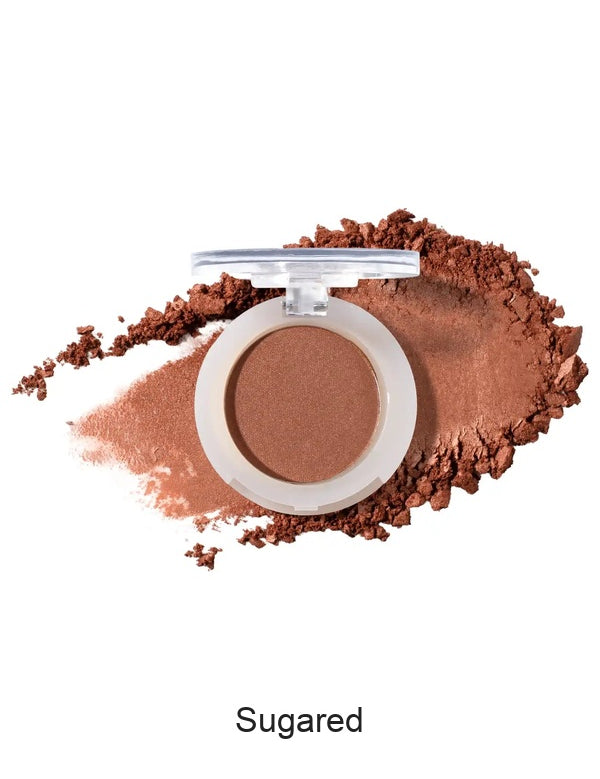 100% Pure Fruit Pigmented Eye Shadow in Sugared, showing an open compact beside a sweep of matching loose powder on white, with the shade name Sugared printed below.