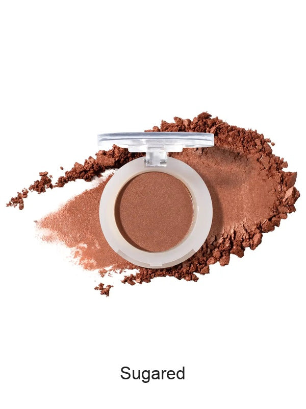 100% Pure Fruit Pigmented Eye Shadow in Sugared, showing an open compact beside a sweep of matching loose powder on white, with the shade name Sugared printed below.