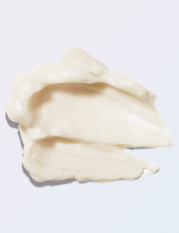 An ivory swatch of 100% Pure Retinol PM Eye Cream on pale lavender, spread into two broad overlapping strokes with thick folded ridges and soft, uneven edges.