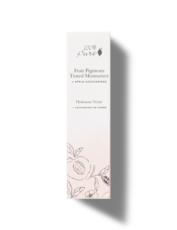 A tall white 100% Pure Tinted Moisturiser carton with black lettering, an apple saccharides label and delicate fruit and leaf drawings around the pale pink base.