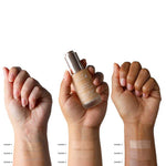 Three hands of varying skin tones show four swatches each (Shade 1–8) of the 100% Pure 2nd Skin Serum Foundation (35ml) on their forearms, with one holding the bottle. Each swatch reveals this ultralight foundation’s natural, seamless coverage.