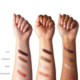 Three forearms with varied skin tones showcase swatches of the 100% Pure Berry Naked Palette 9g—five vegan shades: Vivid, Splendor, Beam, Afterglow, and Illume—demonstrating rich color payoff and long-lasting wear on every complexion.