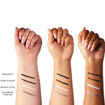 Three raised forearms display swatches of 100% Pure Creamy Long Last Liner 1.14g in Blackest, Dark Cacao, Bright Eyes, and Gleaming Pewter—demonstrating this 100% Pure eyeliner on various skin tones.