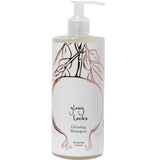 A clear pump bottle of 100% Pure Glossy Locks Glossing Shampoo, with a white label featuring a minimalist line drawing of pomegranate branches and leaves.