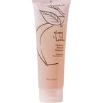 A peach-colored tube of 100% Pure Glossy Locks Moisture Drench Shampoo, a natural moisturizing shampoo featuring minimalist leaf and peach graphics on the packaging, displayed against a white background.