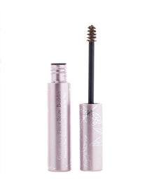 A pink tube of 100% Pure Green Tea Fibre Brow Builder 4.5g with white floral designs stands open, showing its wand applicator with vegan brown brow gel on the brush.