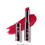A 100% Pure Fruit Pigmented® Lip Glaze 2.5g in Coraline with the cap off and a red swatch behind it. The silver tube has a decorative fruit pattern and the brand name, 100% Pure.