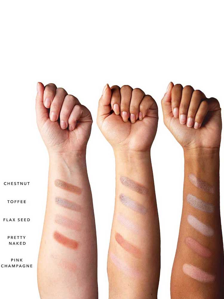 Three forearms with various skin tones show swatches of the 100% Pure Pretty Naked Palette 9g—five vegan shades (Chestnut, Toffee, Flax Seed, Pretty Naked, Pink Champagne) arranged in rows from wrist to forearm.