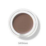 A round 100% Pure Long Last Brows 4.5g container with soft brown cream is shown from above, labeled Soft Brown. This vegan formula by 100% Pure also works as a natural brow gel for an effortless, long-lasting look.