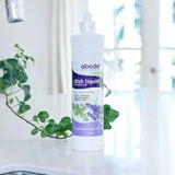 Abode Dishwashing Liquid Lavender and Mint bottle on a kitchen bench beside the sink with trailing ivy