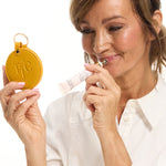 Woman applying The Jojoba Company Ultimate Plumping Lip Treatment with a compact mirror