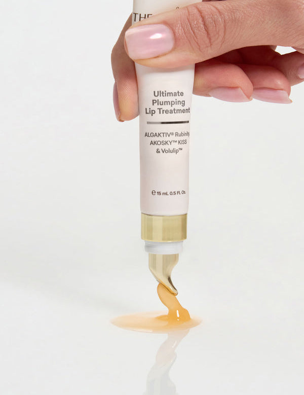 Hand squeezing The Jojoba Company Ultimate Plumping Lip Treatment from the tube