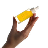 Hand holding a bottle of The Jojoba Company Jojoba Boost Skin Barrier Support