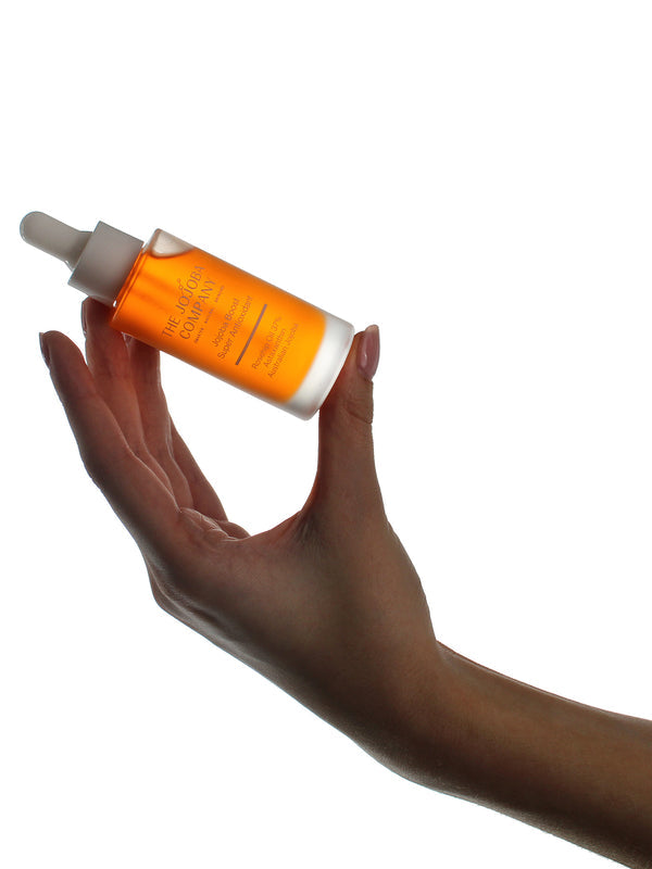 Hand holding a bottle of The Jojoba Company Jojoba Boost Super Antioxidant