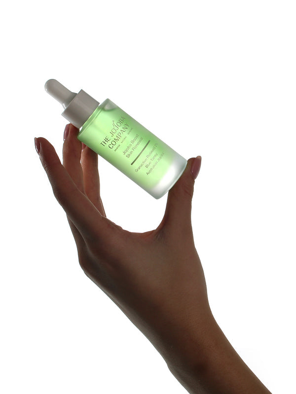 Hand holding a bottle of The Jojoba Company Jojoba Boost Skin Renewal