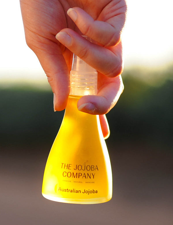 Hands holding the 85ml bottle of The Jojoba Company Australian Jojoba