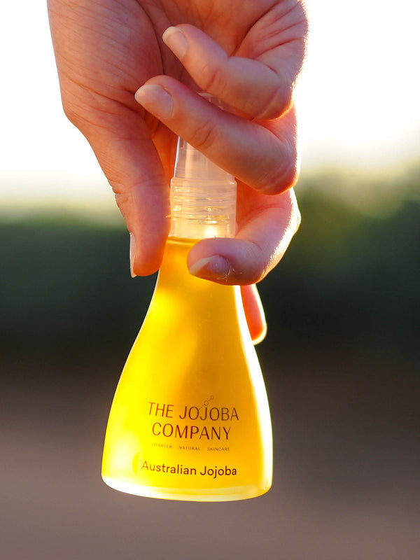 Hands holding the 85ml bottle of The Jojoba Company Australian Jojoba