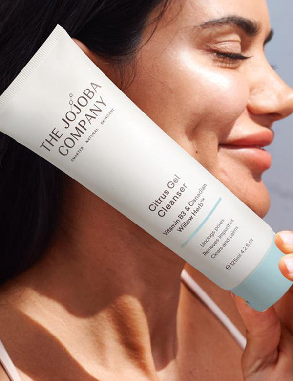 Woman holding a tube of The Jojoba Company Citrus Gel Cleanser