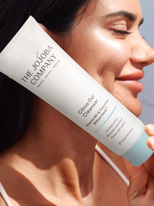Woman holding a tube of The Jojoba Company Citrus Gel Cleanser