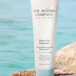 The Jojoba Company Citrus Gel Cleanser tube on a rock by the water