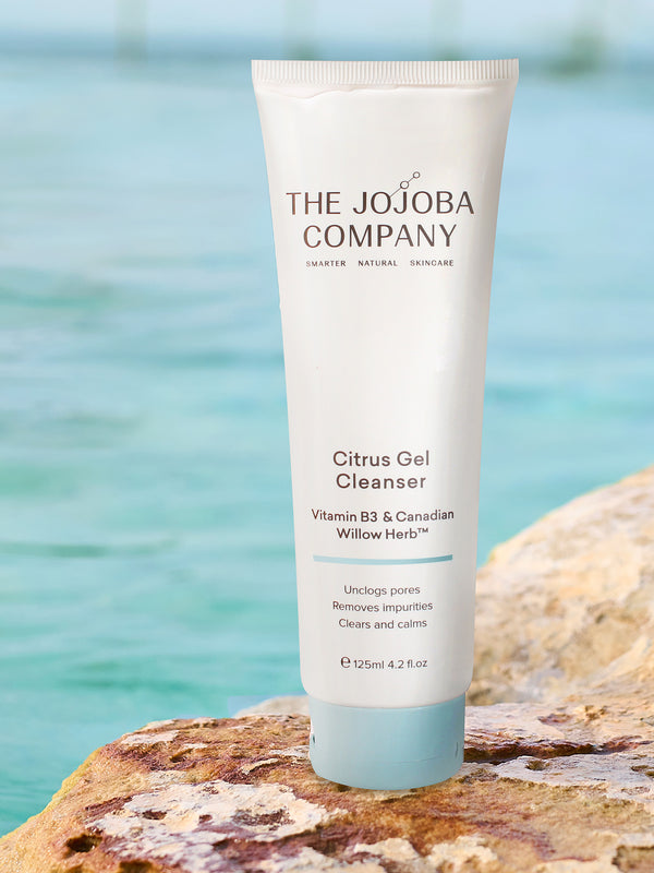 The Jojoba Company Citrus Gel Cleanser tube on a rock by the water