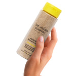 Hand holding The Jojoba Company Jojoba Bean Natural Exfoliant bottle