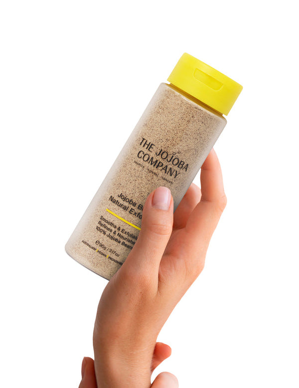 Hand holding The Jojoba Company Jojoba Bean Natural Exfoliant bottle