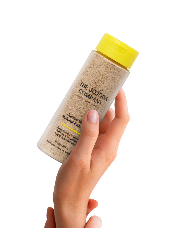 Hand holding The Jojoba Company Jojoba Bean Natural Exfoliant bottle