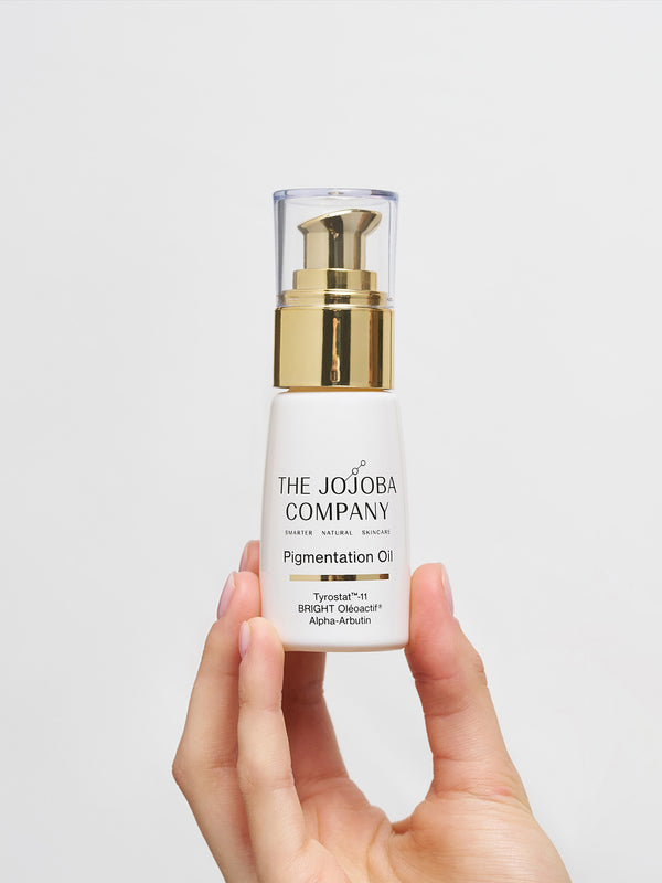 Hand holding a bottle of The Jojoba Company Pigmentation Oil