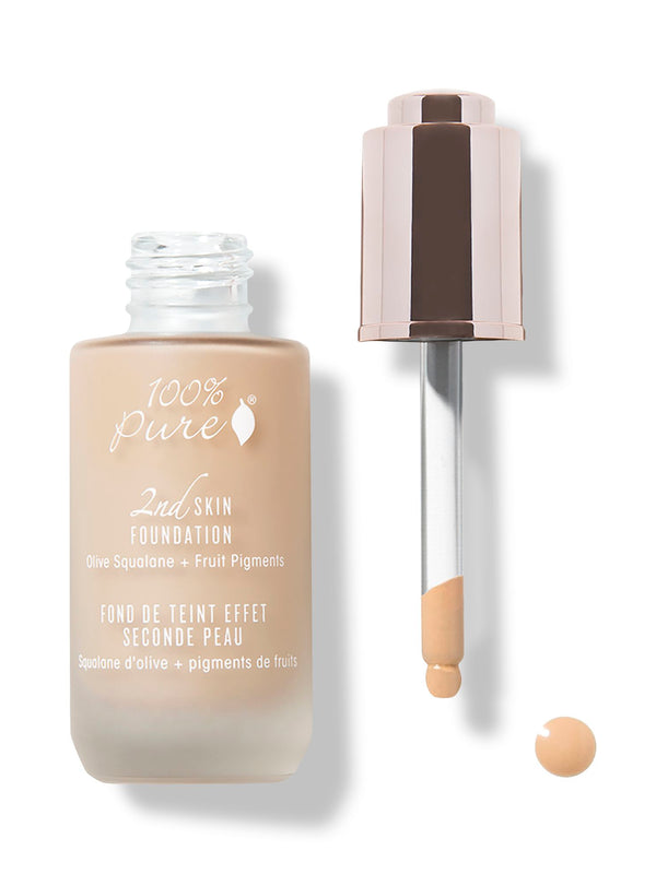 An open frosted bottle of beige 100% Pure 2nd Skin Serum Foundation stands beside its rose-gold dropper cap. Foundation coats the end of the glass pipette, with a small drop below it.