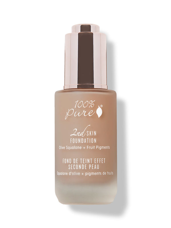 A closed frosted glass bottle of tan 100% Pure 2nd Skin Serum Foundation stands upright with white lettering and a tall reflective rose-gold dropper cap.