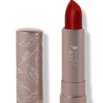 100% Pure Blood Orange matte lipstick with a slanted deep warm red tip extended from a taupe tube; its matching cap stands beside it with white botanical line drawings.