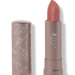 100% Pure Cassia matte lipstick with a slanted warm terracotta rose tip extended from a taupe tube; its matching cap stands beside it with white botanical line drawings.