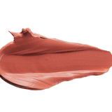 A thick smear of warm terracotta rose Cassia matte lipstick on white, with a smooth centre and raised, creamy ridges around the edges.
